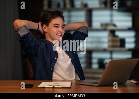 Jeune entrepreneur enthousiaste regardant l'écran d'ordinateur portable, souriant Banque D'Images