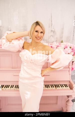 Belle dame en robe rose et piano rose Banque D'Images