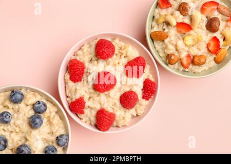 Bols avec savoureux flocons d'avoine, bleuets, framboises et noix sur fond rose Banque D'Images