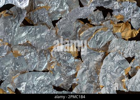 Emballages de bonbons en papier d'aluminium avec le verso pour l'arrière-plan, gros plan, vue de dessus. Beaucoup de beaucoup d'emballage froissé de sous des chocolats Banque D'Images