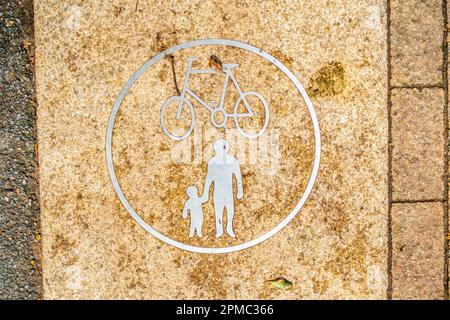 Des symboles sur le sol, estampés dans un chemin, informent les gens que le chemin est destiné aux piétons et aux vélos. Banque D'Images