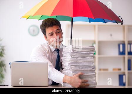 Jeune employé tenant un parapluie sur le lieu de travail Banque D'Images