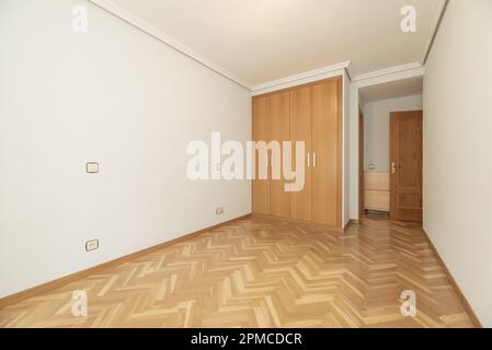 Cette chambre vide comprend une armoire intégrée dotée de quatre portes pliantes en chêne et de parquet vernis brillant Banque D'Images