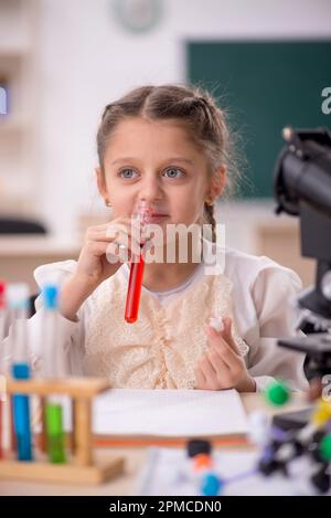 Petite fille étudiant la chimie dans la salle de classe Banque D'Images