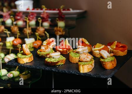 buffet de restauration pour les mariages avec différents en-cas et antipasti. crevettes avec tartiner à l'avocat, bruschetta avec saumon et quartiers de citron. Banque D'Images