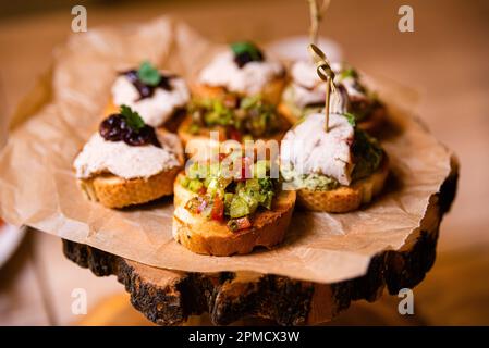 variété de bruschettas avec viande de dinde, légumes en dés, tartiner de thon et oignon caramélisé sur une planche de bois Banque D'Images