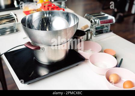 ustensiles de cuisine sur la table dans la cuisine à la maison. bol et casserole en acier inoxydable, cuisinière électrique, bols avec ingrédients Banque D'Images