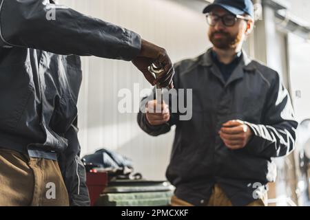 gros plan d'un mécanicien donnant une clé à son collègue dans un atelier de voiture. concept de réparation de voiture. Photo de haute qualité Banque D'Images