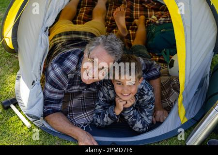 Portrait du grand-père et du petit-fils caucasiens souriants, allongé dans une tente dans la cour Banque D'Images