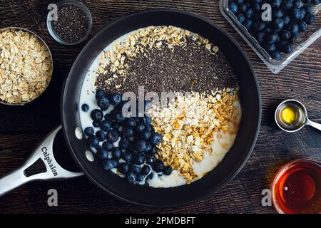 Bleuets Chia flocons d'avoine dans une casserole vue d'en haut: Bleuets, graines de chia, avoine, miel, et autres ingrédients dans le lait d'amande Banque D'Images