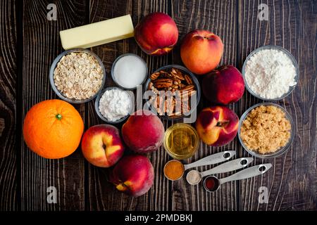 Croustillant aux noix de pécan Bourbon Ingrédients sur une table en bois : pêches fraîches, pacanes et autres ingrédients crus pour un dessert du Sud Banque D'Images