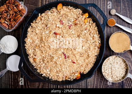 Croustillant de pécan bourbon assemblé avant la cuisson : dessert de pêche non cuit avec du sucre brun, de l'avoine et de la farine dans une poêle en fonte Banque D'Images