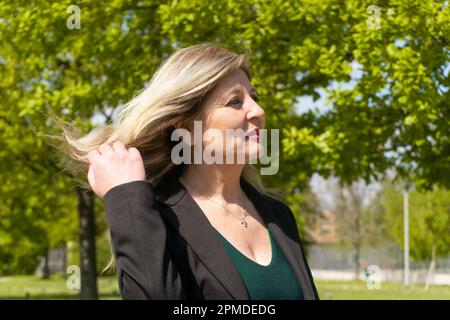 Bonne femme blonde mûre marchant dans le parc Banque D'Images
