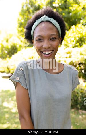 Portrait d'une femme mi-adulte afro-américaine heureuse avec de courts cheveux afro debout dans le parc Banque D'Images