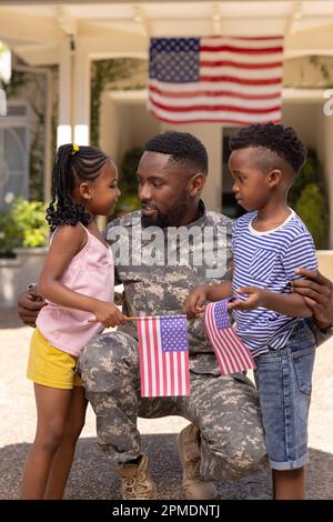 Père soldat de l'armée afro-américaine embrassant et parlant avec des enfants à l'extérieur de la maison Banque D'Images