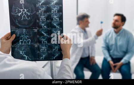 Médecin neurologue examinant l'image IRM cérébrovasculaire du cerveau lors d'une consultation médicale pour un patient souffrant de maux de tête et de vertiges. ARM de la tête Banque D'Images