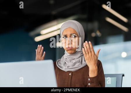 Chaleur et chaleur dans le bureau, femme d'affaires dans le hijab se faisant passer les mains essayant de se rafraîchir et de refroidir, climatiseur cassé sur le lieu de travail. Banque D'Images