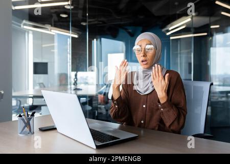 Chaleur et chaleur dans le bureau, femme d'affaires dans le hijab se faisant passer les mains essayant de se rafraîchir et de refroidir, climatiseur cassé sur le lieu de travail. Banque D'Images