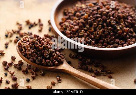 Poivre du Sichuan et cuillère en bois sur la table. Le poivre du Sichuan est un membre de la famille des sansho utilisés dans la cuisine chinoise. Banque D'Images