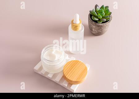 un pot ouvert mat avec hydratant sur un podium de soulagement de plâtre et de sérum dans un flacon blanc mat sur un fond beige. soins cosmétiques Banque D'Images