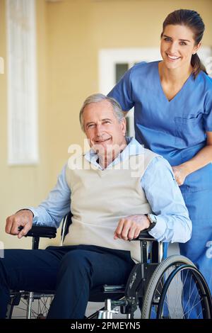 Mes médecins s'assurant que je suis bien pris en charge. un médecin poussant sa patiente en fauteuil roulant. Banque D'Images