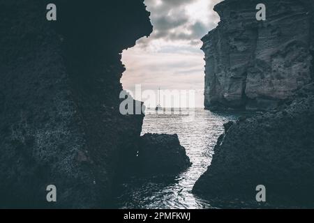 Catamaran à Santorini Caldera à travers les formations rocheuses au coucher du soleil Banque D'Images