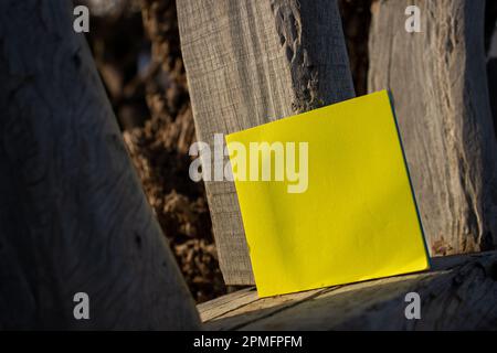 note de papier jaune simple et carrée reposant sur du bois de dérive blanchi avec espace libre vide pour le gabarit ou la zone de copie vierge Banque D'Images