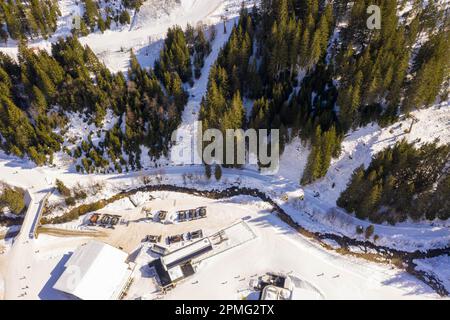 Photographie par drone de remontées mécaniques, rivière, pistes de ciel, machines pendant la journée ensoleillée d'hiver. Directement au-dessus. Banque D'Images