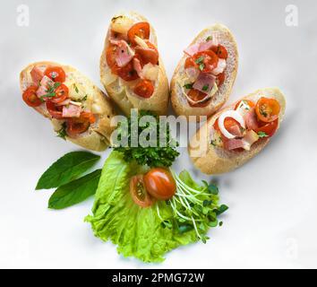 Bruschetta avec tomates, jambon, oignon et huile d'olive sur la plaque blanche Banque D'Images
