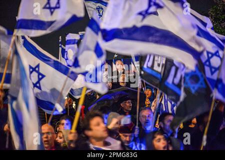 Hadera, Israël. 12th avril 2023. Les manifestants anti-réforme brandient les drapeaux israéliens et tiennent un panneau avec les photos de Netanyahou et de Kim Jong-un qui se mêlent à « Chef suprême » (le mot « cour » est en train d'être barré) lors d'une manifestation. Des manifestants pro et anti-réforme judiciaire à Hadera, manifestaient devant une cérémonie de Mimouna en présence du Premier ministre Benjamin Netanyahu, des affrontements ont eu lieu entre des manifestants anti-réforme et des militants de droite pro-réforme. Crédit : SOPA Images Limited/Alamy Live News Banque D'Images