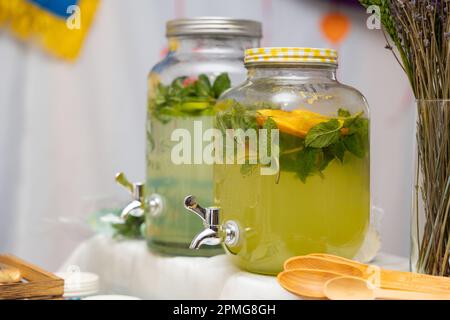 Distributeur de limonade gros plan avec les fruits : pamplemousse, orange, citron. Zone de bienvenue avec boissons aux limonades colorées. Boissons saines sans alcool Banque D'Images