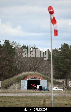 13 avril 2023, Brandebourg, Niedergörsdorf: Derrière une girouette et une piste, vous pouvez voir un vieux hangar d'avion avec un avion microléger. A l'aérodrome 'Altes Lager', il y a eu un accident avec un avion ultraléger. Photo: Michael Bahlo/dpa Banque D'Images