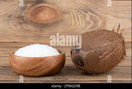 Flocons de noix de coco et de noix de coco entiers dans un bol en bois sur fond de bois. Copier l'espace. Banque D'Images