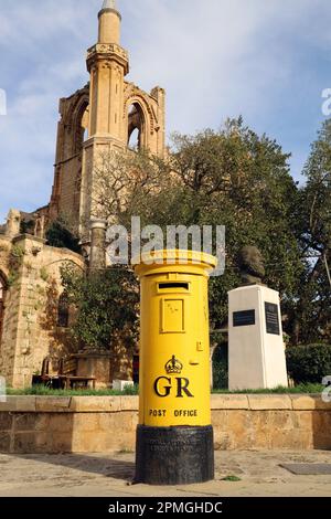 Ancienne boîte jaune de pilier laissée de la période colonialiste britannique avec la mosquée Lala Pasha Mustafa derrière; la vieille ville de Farmagusta (Gazimagusa), Turki Banque D'Images