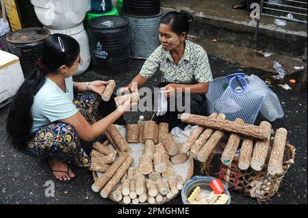 01.08.2013, Yangon, Myanmar, Asie - une scène de marché quotidienne représente une femme qui fait du shopping dans le bois de Thanaka sur un marché de rue dans le centre-ville. Banque D'Images