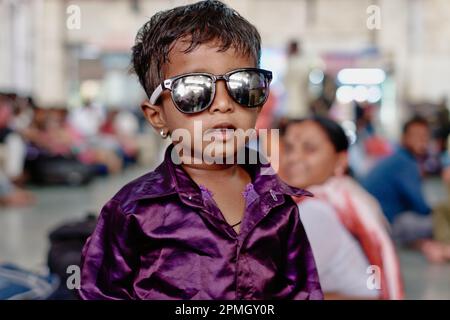 Un garçon indien de maternelle portant des lunettes de soleil ainsi que des boucles d'oreilles, apparemment habillé le long des lignes de célébrités de Bollywood Banque D'Images