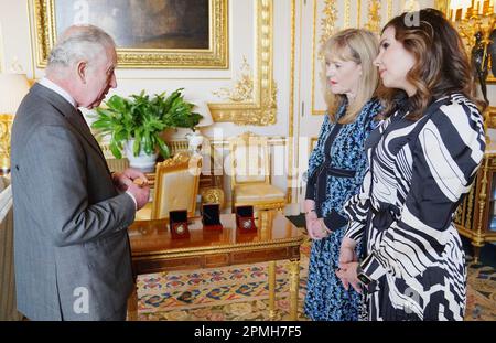 Le roi Charles III reçoit la première pièce de Coronation frappée en £5 par Anne Jessopp, chef de la direction de la monnaie royale (au centre) et Rebecca Morgan (à droite), au château de Windsor, dans le Berkshire. Un portrait couronné du roi sera pour la première fois sur une nouvelle gamme de pièces commémoratives créées pour célébrer le prochain couronnement. La collection, qui comprend une pièce de 50p et £5, sera libérée plus tard ce mois-ci avant la célébration historique de 6 mai. Date de la photo: Jeudi 13 avril 2023. Banque D'Images