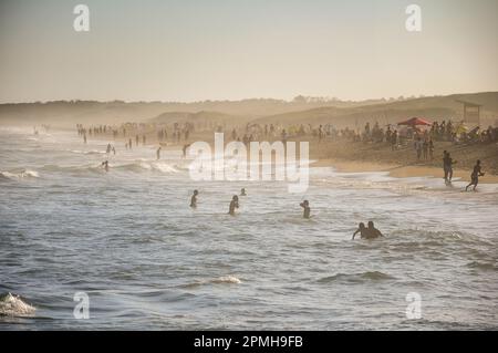 Des dizaines de personnes se baignant dans l'une des plages de Punta del Diablo, au coucher du soleil Banque D'Images