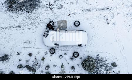 Vue aérienne d'un homme changeant de pneus, par une journée d'hiver nuageux - tir de drone en haut Banque D'Images