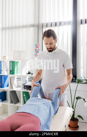thérapeute manuel barbu faisant massage des bras à la femme dans la clinique de réadaptation, image de stock Banque D'Images