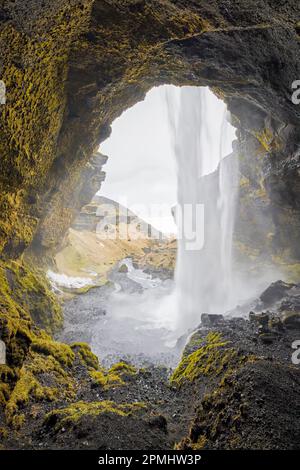 Cascade de Kvernufoss sur la rivière Kverna, vue de l'intérieur d'une petite grotte derrière l'eau en cascade en hiver, Skógar, Rangárþing eystra, Islande du Sud Banque D'Images