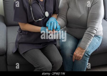 Jeune infirmière soignante médecin soignant aidant à tenir les mains d'une femme handicapée heureuse handicapée ou blessée âgée adulte ayant un problème de santé d'incapacité Banque D'Images