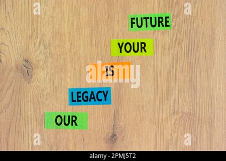 Symbole de l'héritage et du futur. Concept Words notre héritage est votre avenir sur papier coloré. Belle table en bois fond en bois. Héritage commercial et futur Banque D'Images