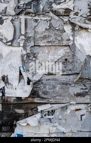 Ancien panneau d'affichage sur un mur en bois rustique avec des restes de vieux papier d'affiches déchirées, fond de texture grunge Banque D'Images