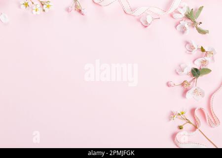 Motif floral avec fleurs sauvages, feuilles vertes, branche sur fond rose. Pose à plat Banque D'Images