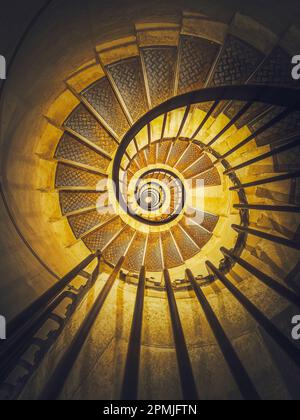 Escalier en colimaçon abstrait perspective avec vue en bas à l'infini tourbillon des escaliers dans la lumière jaune éclatant Banque D'Images