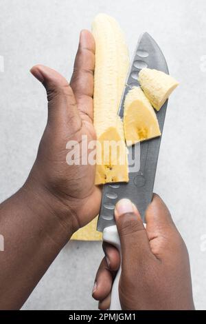 Les mains tranchant des plantains, tranchant des plantains jaunes pour la friture, le processus pour faire des plantains frits Banque D'Images
