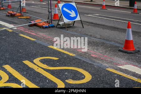 Flèche bleue, à côté des cônes orange de roadworks, texte jaune de bus sur l'asphalte à proximité Banque D'Images