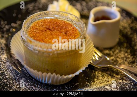 Petit cheesecake au dessert sucré dans un verre de sauce aux fruits et de crème fouettée sur une assiette noire Banque D'Images