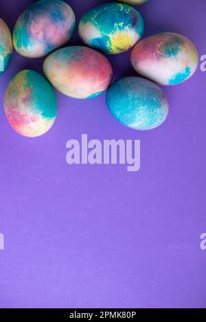 Composition de Pâques avec œufs colorés dans un panier, lapin en bois et fleurs printanières sur fond violet. Cadre de Pâques d'oeufs peints en violet c Banque D'Images